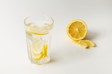  A glass of fresh cool water with lemon slices on a white background