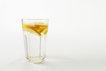 A glass of fresh cool water with lemon slices on a white background