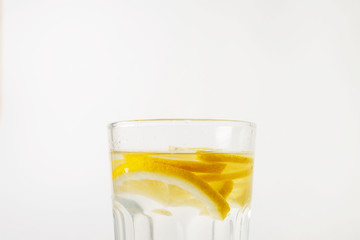  A glass of fresh cool water with lemon slices on a white background