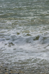 sea landscape is a pebbly beach with waves in white foam
