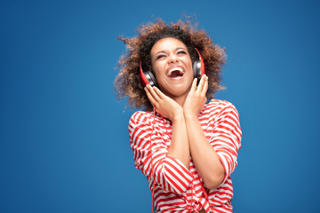 Adorable happy afro girl with red headphones laughing.