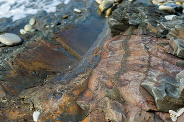 pebble stones on the sea beach, the rolling waves of the sea with foam