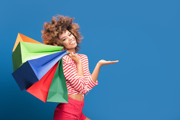 Happy afro girl holding colorful shopping bags.