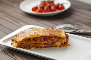 Tasty lasagne with meat covered with cheese served on white plate. 