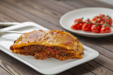 Tasty lasagne with meat covered with cheese served on white plate. 