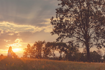 Girl enjoying in the meadow at golden sunset time.