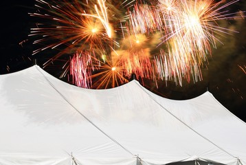large marquee white events tent with fireworks lighting up the night sky behind © mgs