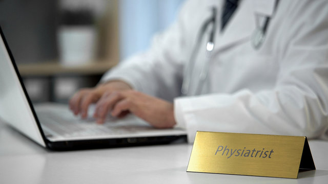 Physiatrist prescribing medication to patient, filling out forms in office