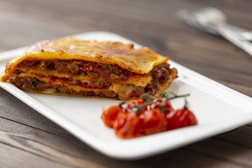 Tasty lasagne with meat covered with cheese served on white plate.  