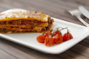Tasty lasagne with meat covered with cheese served on white plate.  