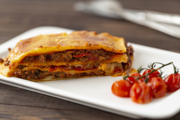 Tasty lasagne with meat covered with cheese served on white plate.  