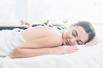 Obraz na płótnie Canvas Hot stone massage treatment by therapist in spa.