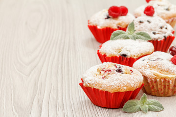 Homemade cupcakes sprinkled with powdered sugar and fresh raspberries