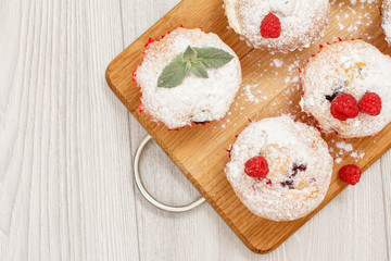 Homemade fruit muffins sprinkled with powdered sugar and fresh raspberries