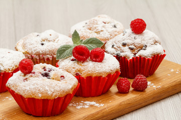 Homemade fruit muffins sprinkled with powdered sugar and fresh raspberries