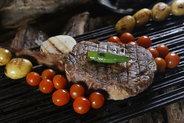 Grilled Tomahawk served with roasted chiles, potatoes and cherry tomatoes. This steak with the long...