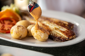 Close up of tasty fried fish and sea fruits with potato and sauce from tomato and chili re paper....