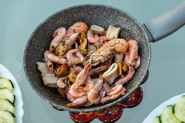 View of delicious and tasty homemade Spanish or Canarias dish, with sea fruits. Healthy dinner outside for two people. Vegetables, Italian pasta with tomato sauce. View of palm tree.