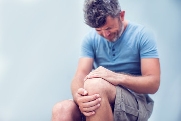 Closeup man hand holding knee with pain on bed, health care and medical concept