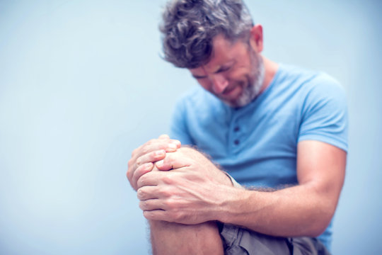 Closeup Man Hand Holding Knee With Pain On Bed, Health Care And Medical Concept