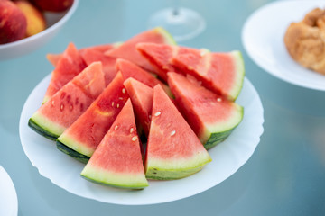 View of tasty breakfast on glass table, juice fruits, nectarine, watermelon, pineapple, water and bake. Healthy, colorful and exotic food in paradise. Summertime concept. Palm leaf on background.