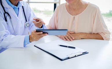 Patient listening intently to a male doctor explaining patient symptoms or asking a question as they discuss paperwork together in a consultation