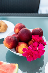 View of tasty breakfast on glass table, juice fruits, nectarine, watermelon, pineapple, water and bake. Healthy, colorful and exotic food in paradise. Summertime concept. Palm leaf on background.