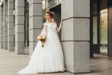 Obraz premium Beautiful bride in luxurious white dress on a city street.