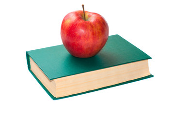 Ripe, red apple lies on a green book isolated on a white background