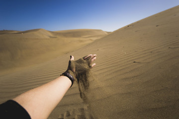 woman hand is holding sand but sand is falling down because of gravitation and wind, makes new creations