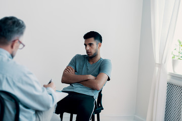 Angry, rebellious teenager talking to a psychiatrist in a juvenile detention center - obrazy, fototapety, plakaty