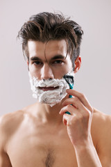 Young handsome man is shaving his beard. 