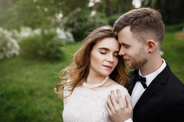 Fototapeta premium Elegant gorgeous bride and stylish groom posing in the park. 