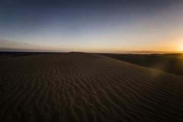 dunes in desert are sandy and are all the time in the move, wind is blowing the sand and making new hills, shapes and creations