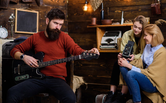 Bearded man in terracotta knitted pullover and black jeans wearing ring with huge gem stone, fashion concept. Man with stylish beard posing with electrical guitar, musical instruments store promo