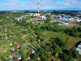 Heating plant with high chimney in city, close to the allotment gardens, aerial view