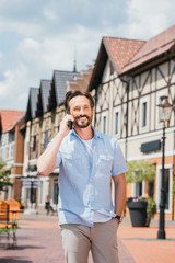 smiling handsome man talking by smartphone in city