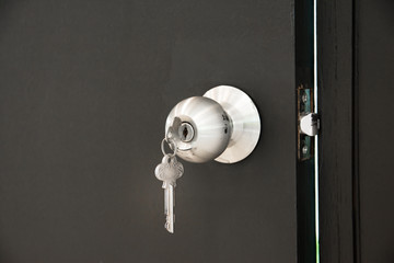 Door knob with key on wood door background