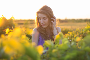 Young beautiful woman in purple dress having good time in summer vineyard during sunset