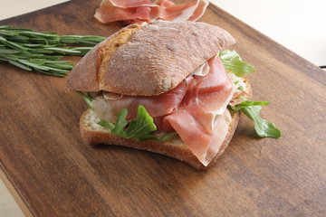 sandwich with prosciutto jamon on a wooden background