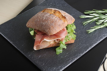 sandwich with prosciutto jamon on a stone background