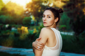 Outdoor close up portrait of young beautiful brunette girl, hair twisted in two bows, no makeup. Model posing in street. Summer sunny day. Female natural beauty, happiness concept