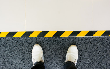 Mind your step line on the floor with men feet standing at entrance gate background