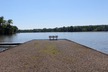 The empty bench on the waterfront of the lake in the park.