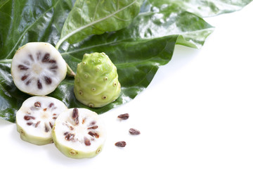 Fototapeta na wymiar Noni fruit or Morinda Citrifolia and noni slice with seed and green leaves of the noni isolated on white blackground with copy space for text. With clipping path.