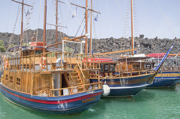 Fototapeta na wymiar Wooden ships on port of Nea Kameni volcanic island near Santorini