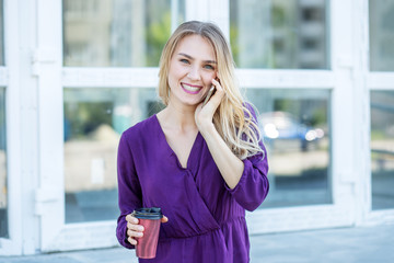 Young girl speaks on the phone and smiles on the street. Concept of life style, urban, work.