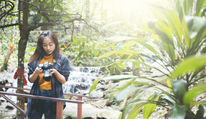 Naklejka na ściany i meble Photography and travel The girl holding the camera in humid forest zone.