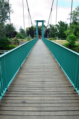 Fototapeta na wymiar Stalowy most wiszący z drewnianym podestem.