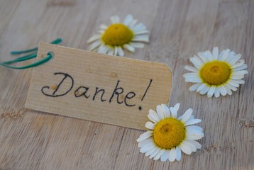 Grußkarte mit Margeriten auf einem Holztisch